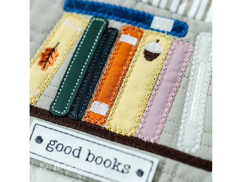 A quilted fabric piece features a row of colorful books on a shelf, with "good books" text.