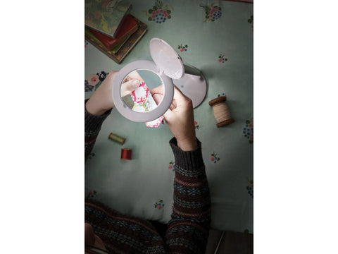 Daylight Halo Go Rechargeable Magnifier held by hands sewing fabric.