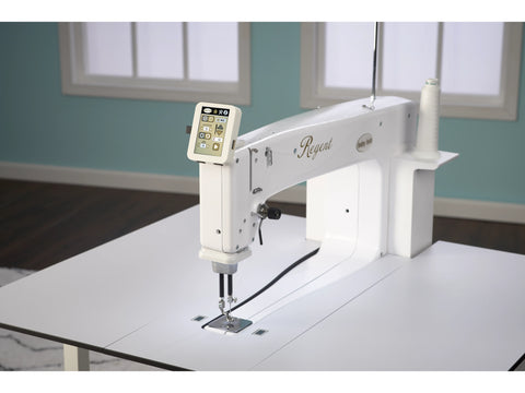 A white Baby Lock Regent 18" sit-down quilting machine with a digital display and thread spool.