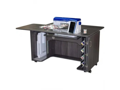 A dark wood sewing and embroidery cabinet with a sewing machine, fabric, and thread spools.