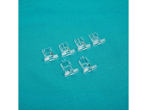 Six clear plastic cording and taping micro insert feet are arranged on a teal fabric.