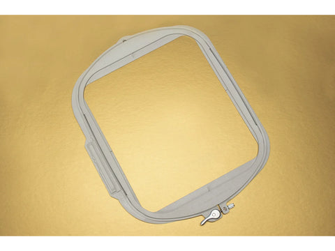 A gray, square embroidery hoop with a metal lever, on a gold background.