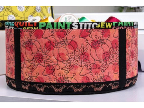 A round fabric storage bin with a floral pattern and sewing-themed text.