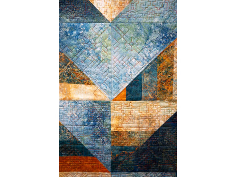 A close-up of a quilt with blue, orange, and brown geometric patterns.