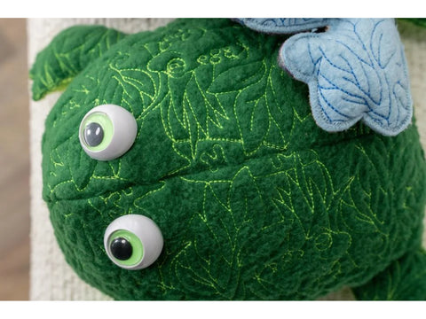 A green plush toy with large eyes and light blue wings.