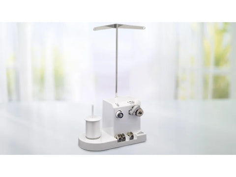 A white Baby Lock bobbin winder with a tall metal thread stand.