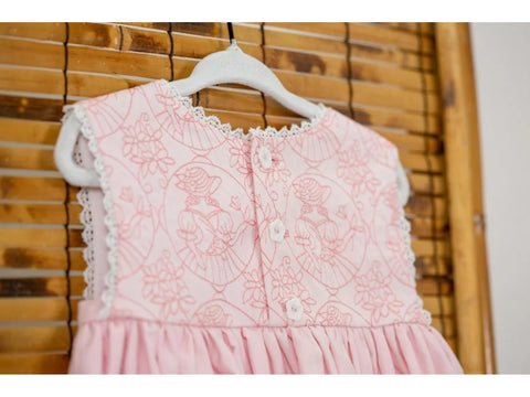A pink baby dress with white lace trim and embroidered floral and character designs.