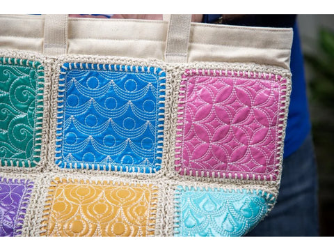 A close-up of a colorful quilted tote bag with various embroidered patterns.