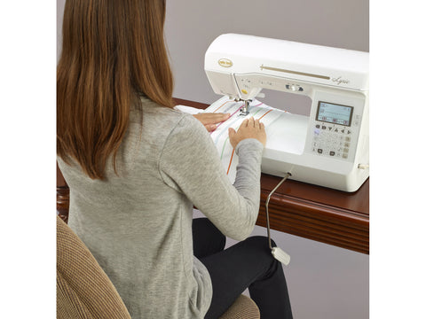 A woman sews on a white Baby Lock Lyric sewing and quilting machine.