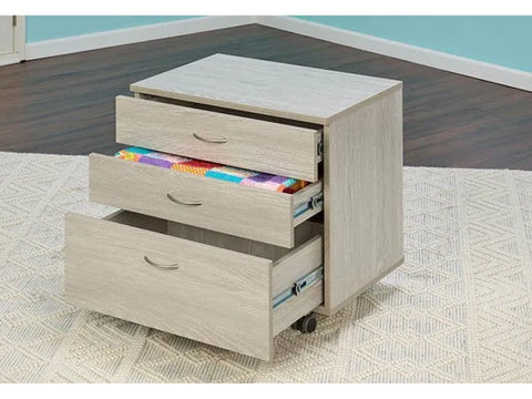 Light wood grain sewing and companion chest with three open drawers, one holding colorful fabric.