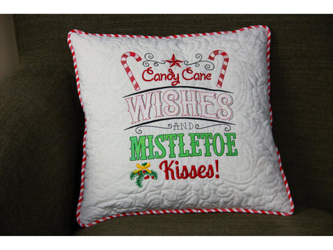 White quilted pillow with red and green "Candy Cane Wishes and Mistletoe Kisses!" embroidery.