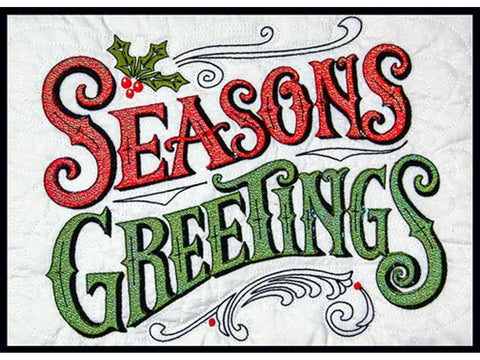 A white quilted fabric features "SEASONS GREETINGS" in glittery red and green letters with holly accents.
