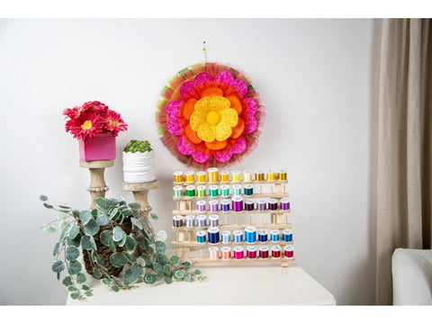 A wooden thread rack holds colorful spools of thread, with decorative items nearby.