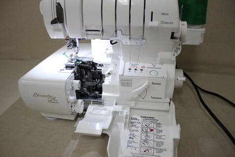 A white Baby Lock Accolade serger with green thread is open, revealing its threading mechanism.