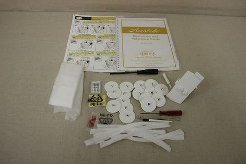 A Baby Lock Accolade serger instruction manual and accessories are laid out on a surface.
