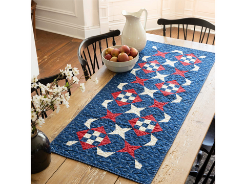 A quilted table runner with a red, white, and blue star and checkerboard pattern.