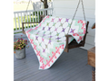 A colorful quilt with a nine-patch star pattern draped over a wooden porch swing.