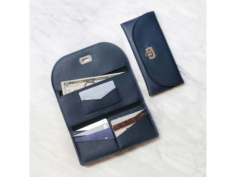 An open and closed navy blue faux leather wallet with a five-dollar bill and cards inside.