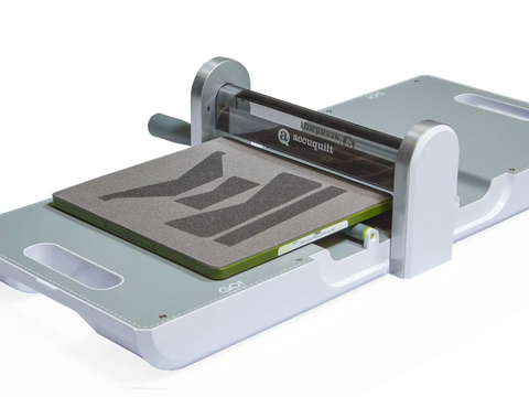 A white and gray AccuQuilt GO! fabric cutter with a die set for a lucky penny wallet.