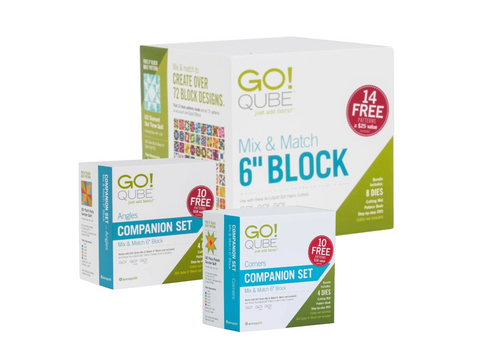 Three white boxes of AccuQuilt Qube sets are stacked, with the largest box at the back.