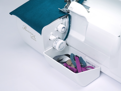 A white Baby Lock serger with a trim bin full of fabric scraps.