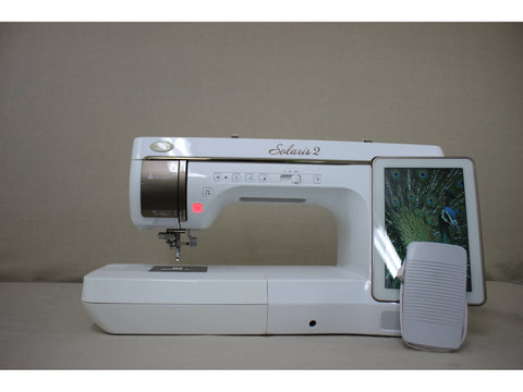A white Baby Lock Solaris 2 sewing and embroidery machine with a screen displaying a peacock feather.