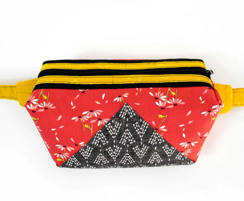 A red floral and black patterned fanny pack with a yellow strap and zipper.