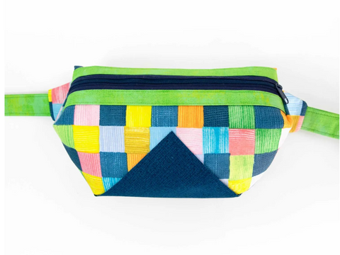 A colorful quilted fanny pack with a navy zipper and a dark blue triangular accent.