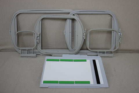 Four embroidery hoops and a white and green placement mat are on a light gray surface.