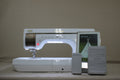 A white Baby Lock Solaris sewing and embroidery machine with a touchscreen and foot pedal.