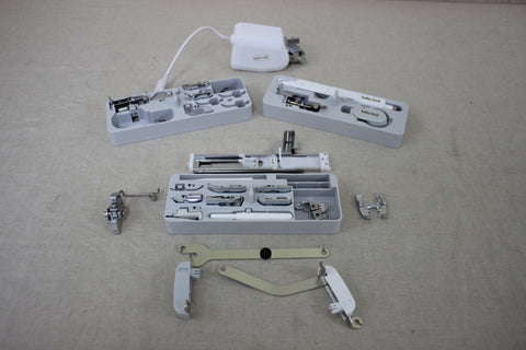 A collection of sewing machine accessories, including presser feet and tools, in various cases.