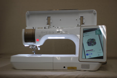 A white Baby Lock Solaris 2 sewing and embroidery machine with a screen displaying a floral design.