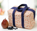 An insulated lunchbox tote in a pink floral pattern with navy straps.