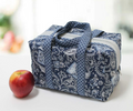 An insulated lunchbox tote in a blue paisley pattern with an apple beside it.