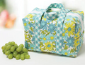 A white insulated lunchbox tote with blue and yellow floral and checkered patterns.